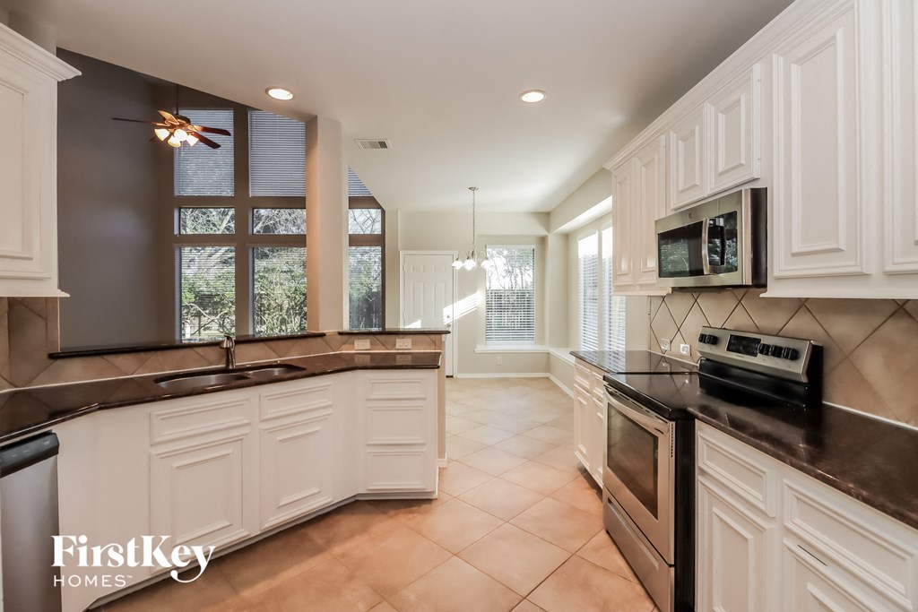 a kitchen with black counter tops and white cabinets and a window