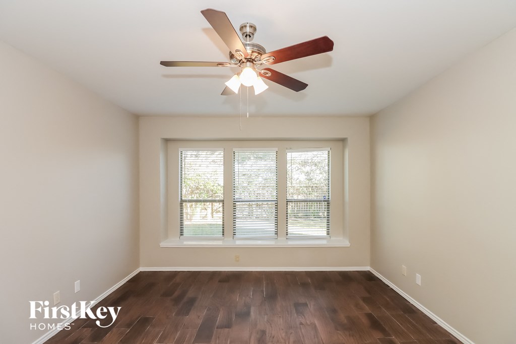 a bedroom with a large window and a ceiling fan