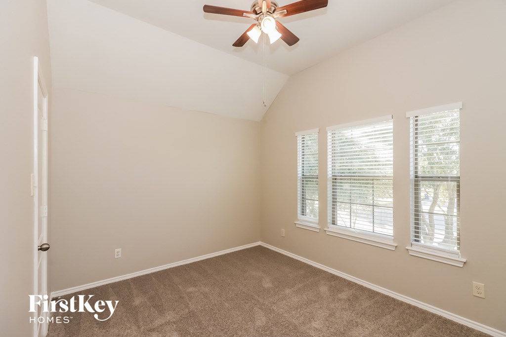 a bedroom with a ceiling fan and three windows