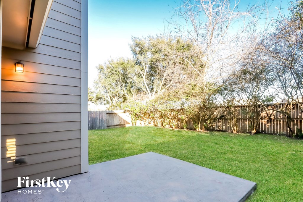 a backyard with green grass and a fence and a house