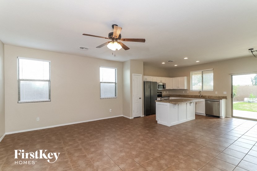 A spacious kitchen and living room with a ceiling fan and tiled flooring.