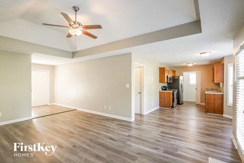A spacious living room with a ceiling fan and wooden flooring.