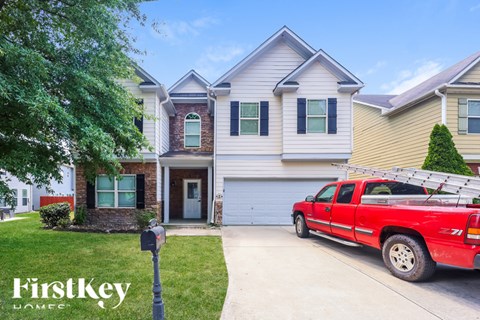 A red pickup truck is parked in front of a two-story house.