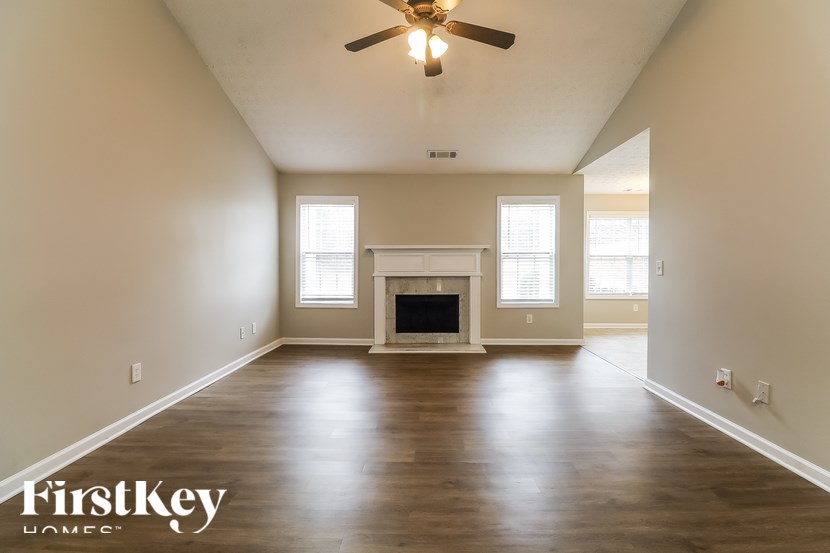 A spacious room with a fireplace and a ceiling fan.
