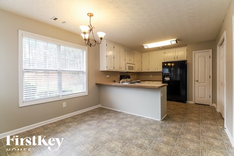 A kitchen with a black refrigerator and white cabinets.