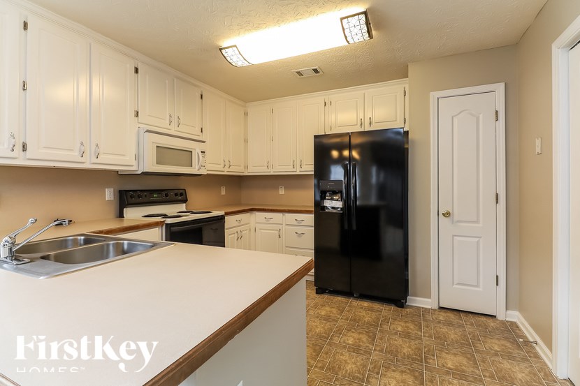 A kitchen with a black fridge and white cabinets.