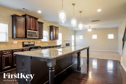 a kitchen with a large island with granite counter tops and dark wood cabinets