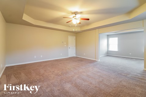 the spacious living room with carpeting and a ceiling fan