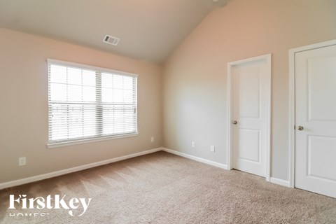 a bedroom with carpet and a window and two doors
