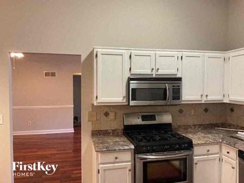 A kitchen with white cabinets and a black stove top oven.