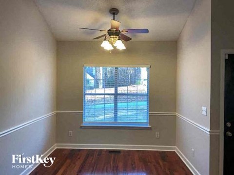 A room with a ceiling fan and a window overlooking a pool.
