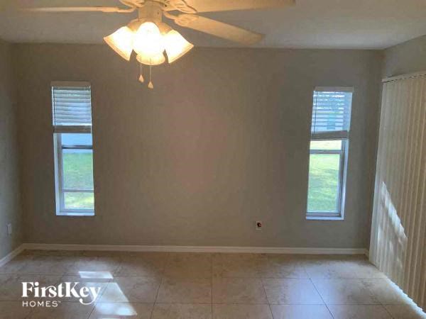 A room with a ceiling fan and two windows.