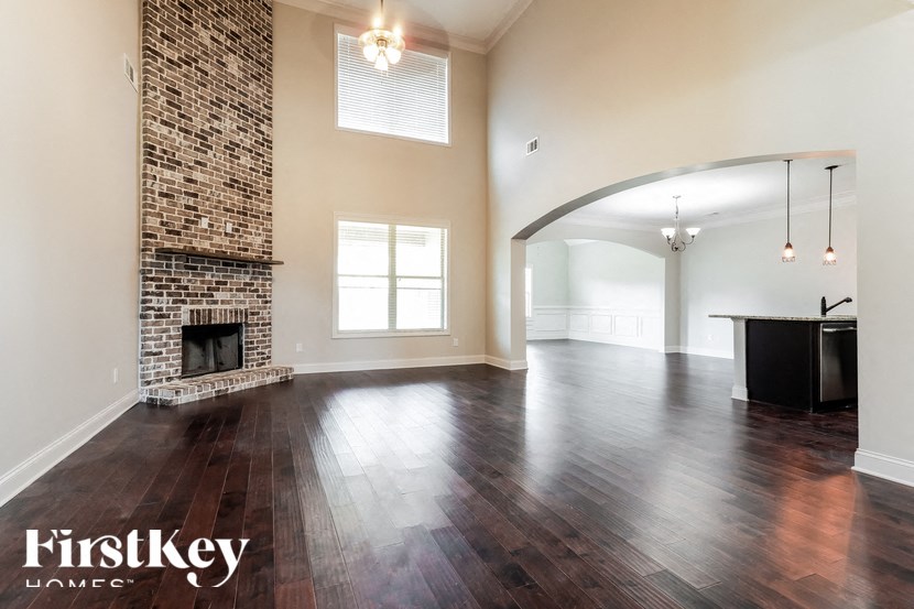 A spacious room with a fireplace and wooden floors.