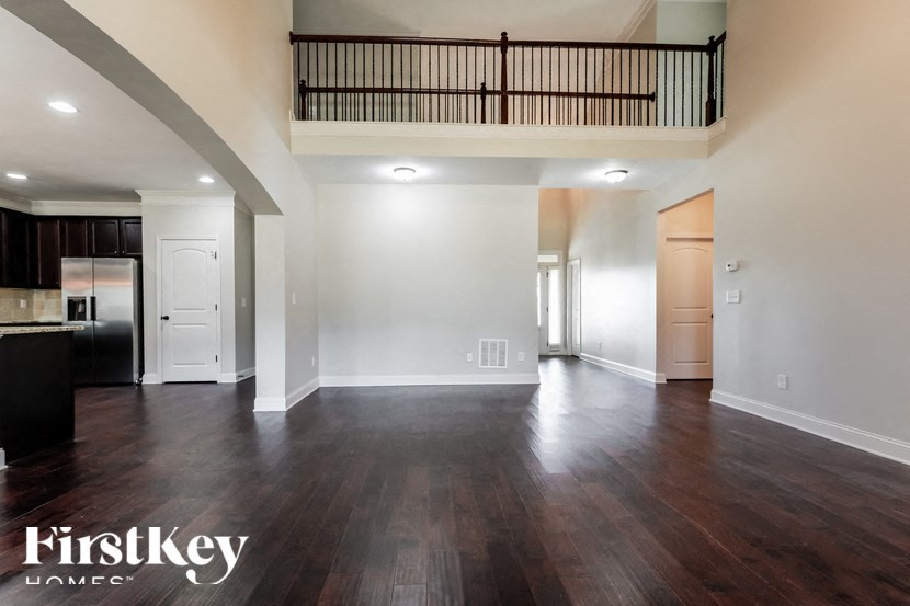 A spacious living room with wooden floors and a balcony.