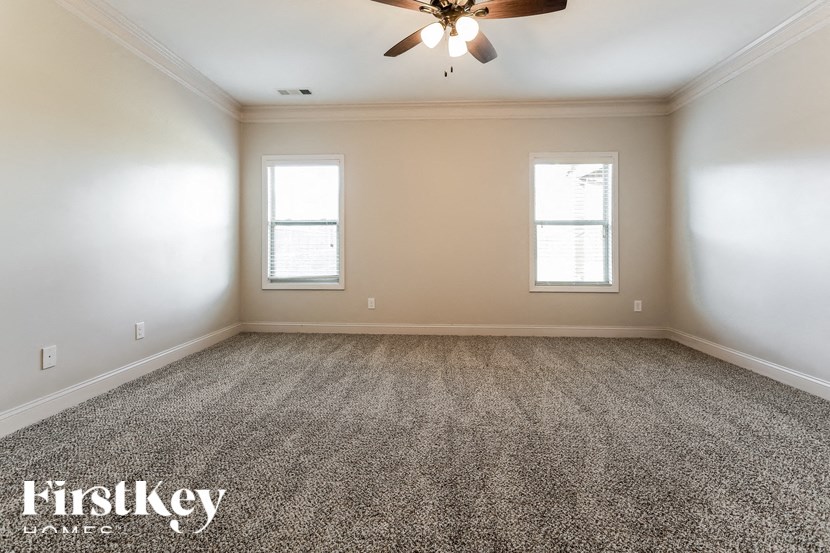 A spacious room with a carpeted floor and a ceiling fan.