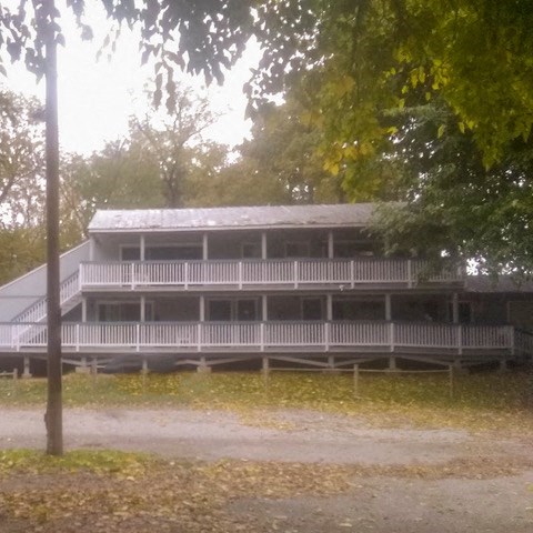 a large white building with a porch and trees