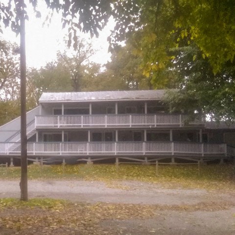 a large white building with a porch and trees