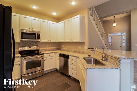 A kitchen with a refrigerator on the left and a stove top oven.
