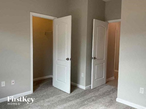an empty bedroom with three doors and a carpet floor