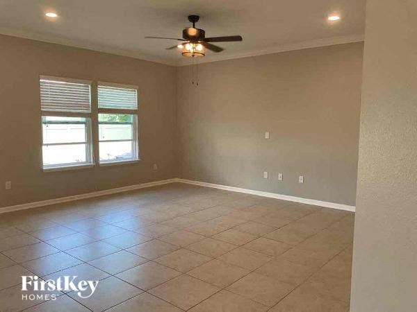 an empty living room with a ceiling fan and a tiled floor