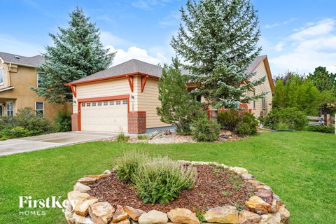 a round rock retaining wall in front of a house