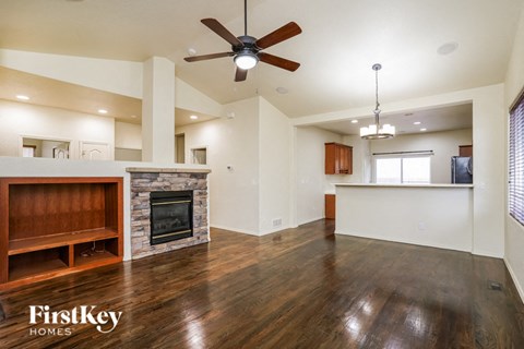 an empty living room with a fireplace and a ceiling fan