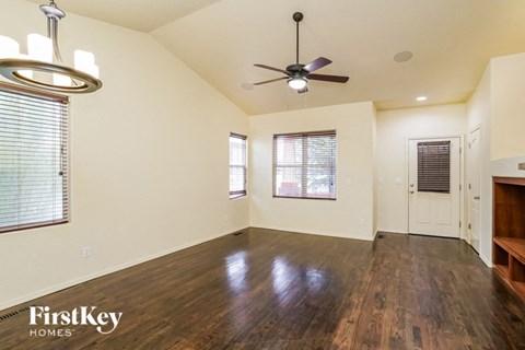 an empty living room with wood floors and a ceiling fan