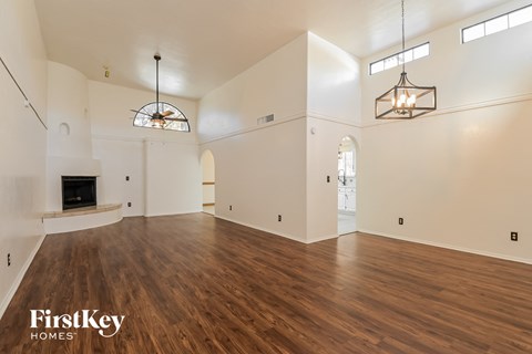 A spacious living room with wood flooring and a fireplace.