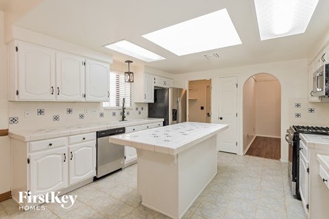 A kitchen with white cabinets and a large island.