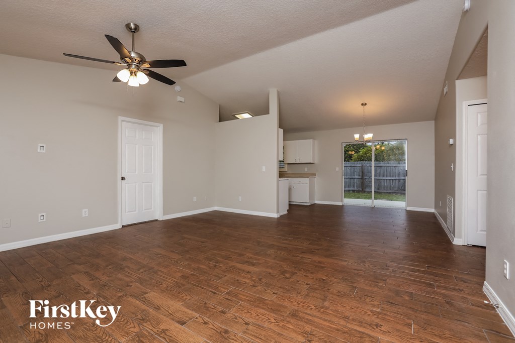 the living room and kitchen of an empty house with a ceiling fan