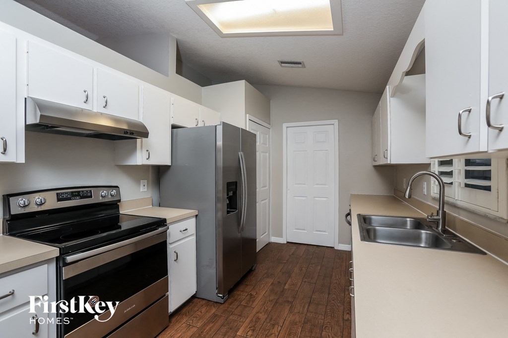 an empty kitchen with stainless steel appliances and white cabinets