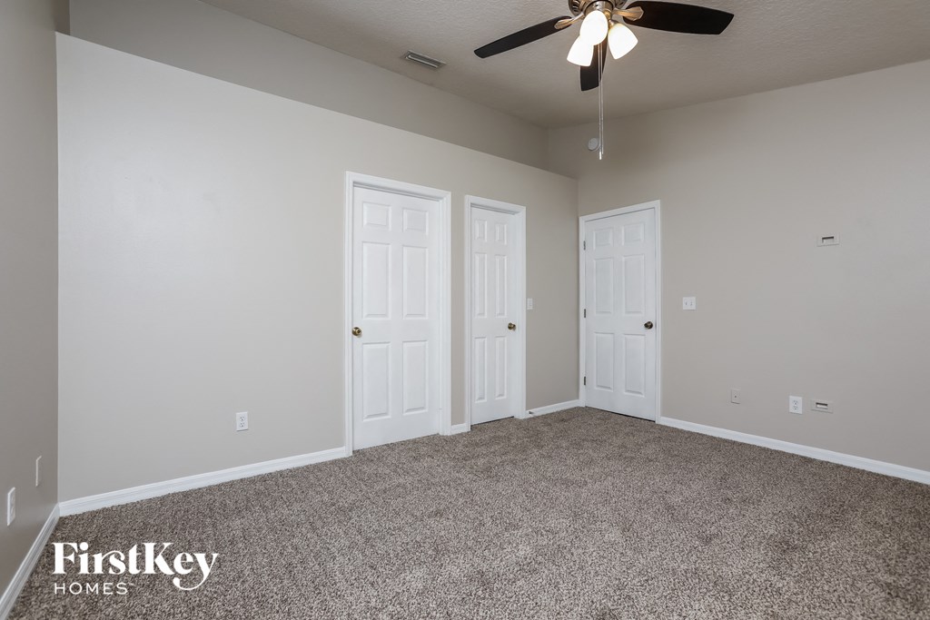 a bedroom with two doors and a ceiling fan
