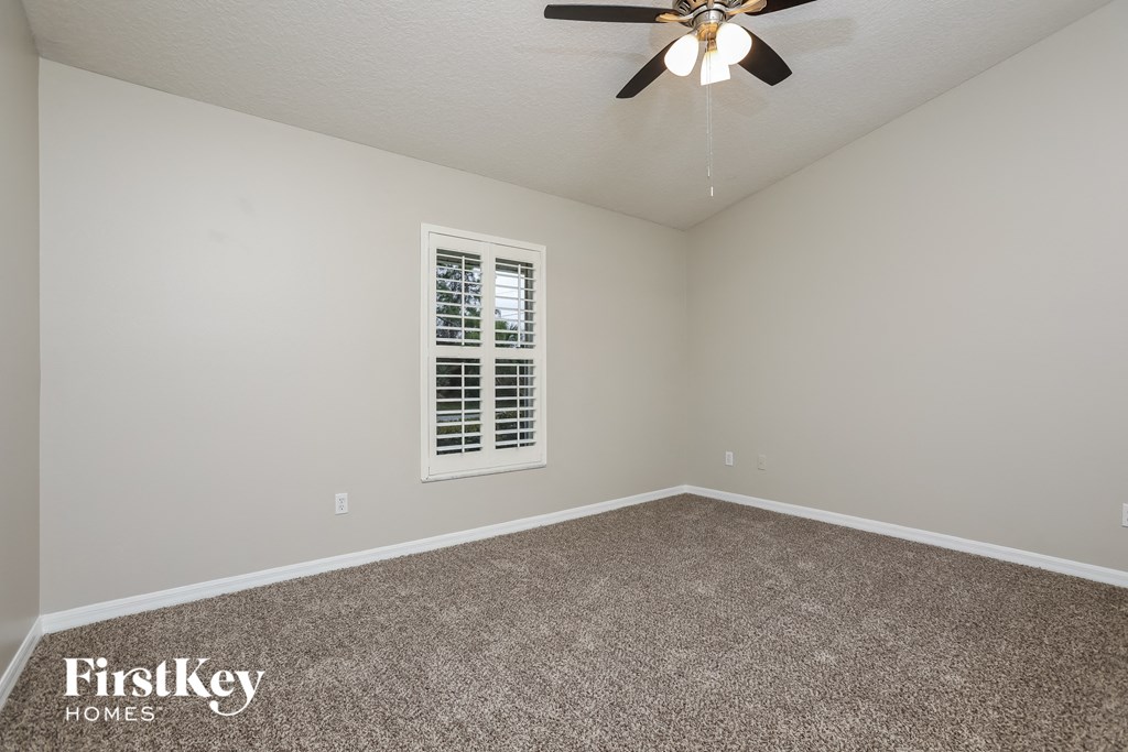 the master bedroom has a carpeted floor and a ceiling fan