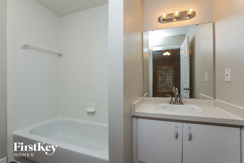 a bathroom with a sink and a tub and a mirror