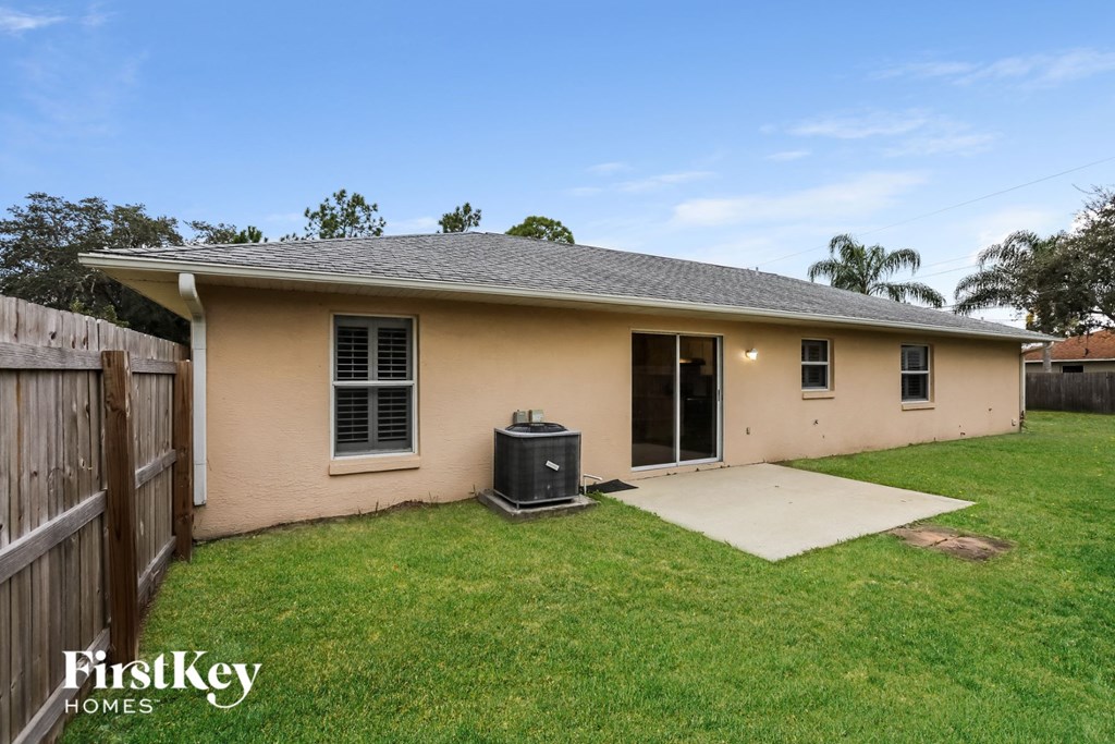 a small tan house with a yard and a backdoor