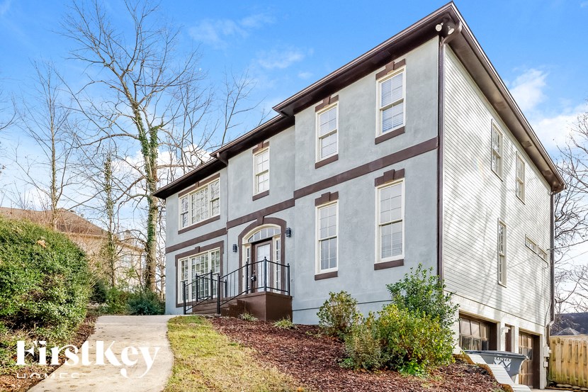 a white and brown house with a sidewalk in front of it