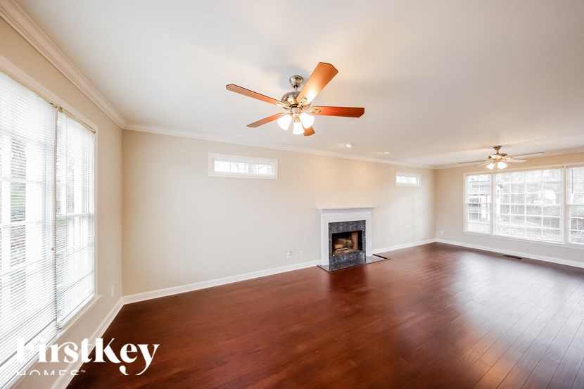an empty living room with a ceiling fan and a fireplace