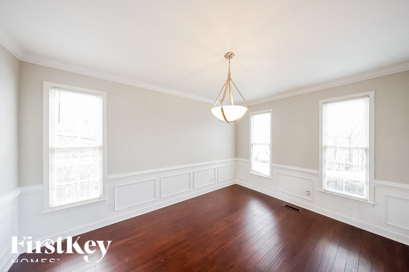 an empty dining room with wood floors and a chandelier