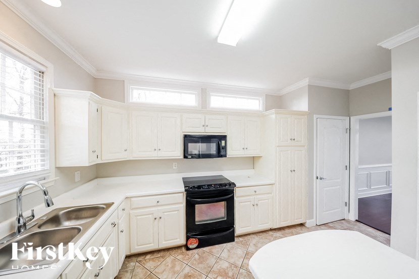 a kitchen with white cabinets and black appliances and a sink
