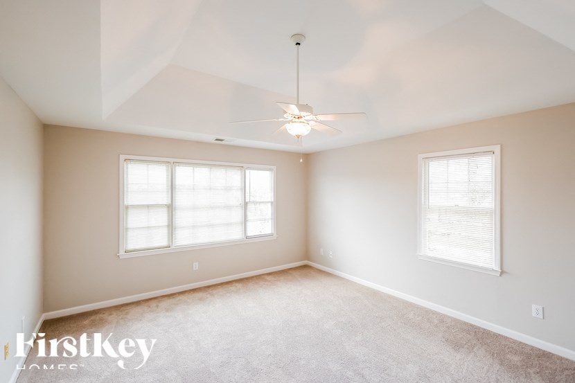 a bedroom with a ceiling fan and two windows