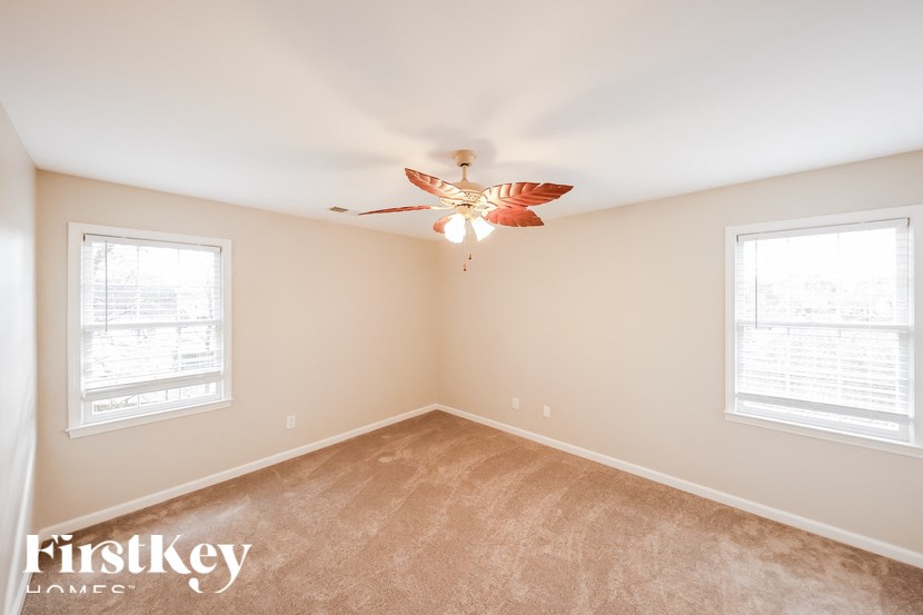 a bedroom with a ceiling fan and two windows