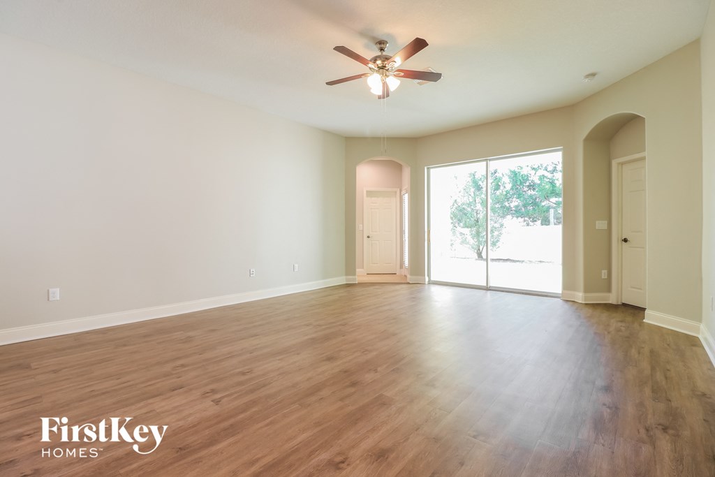 an empty living room with wood floors and a ceiling fan
