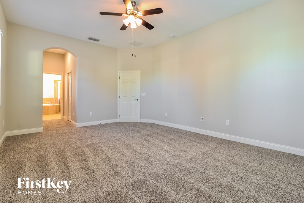 a empty living room with carpet and a ceiling fan