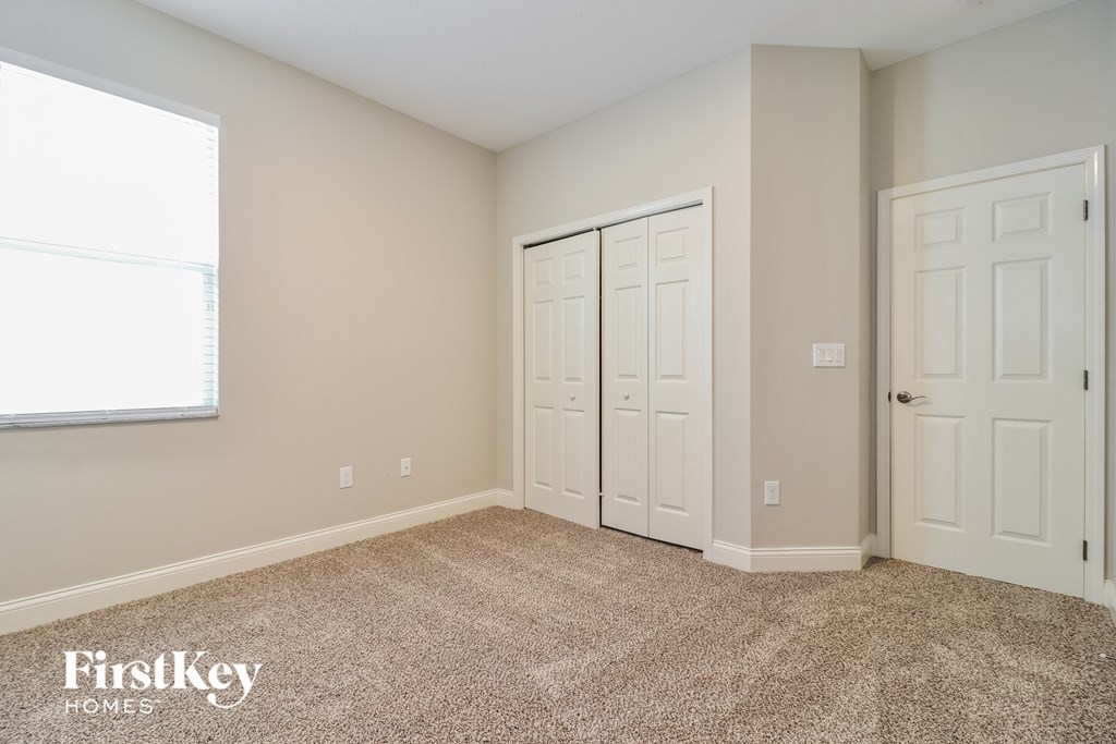 a bedroom with two doors and a window and a carpeted floor