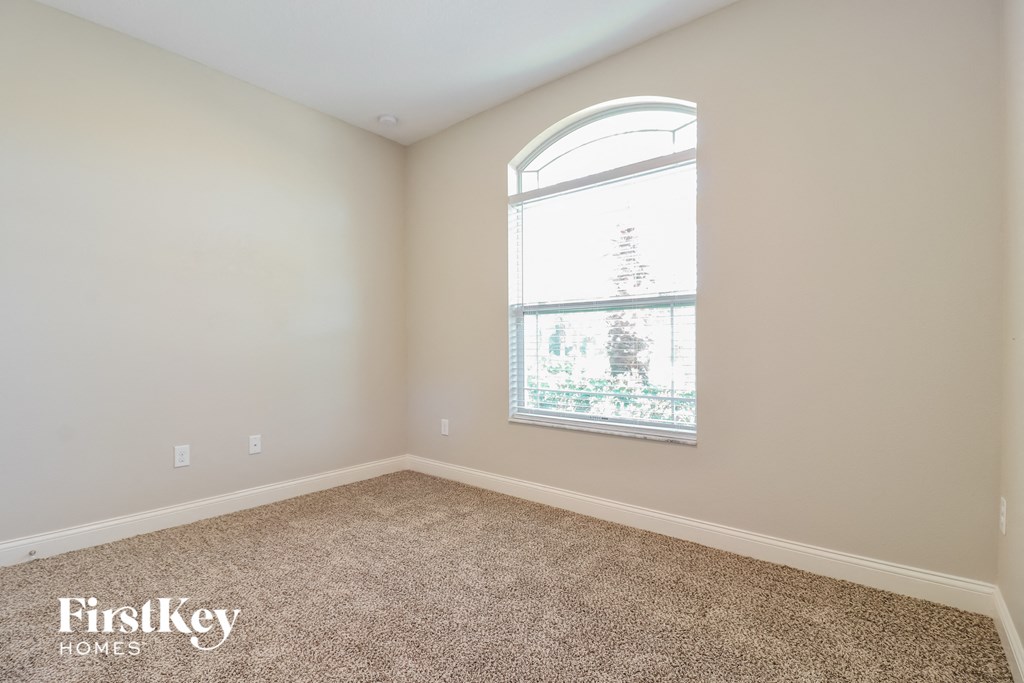 a bedroom with a large window and a carpeted floor