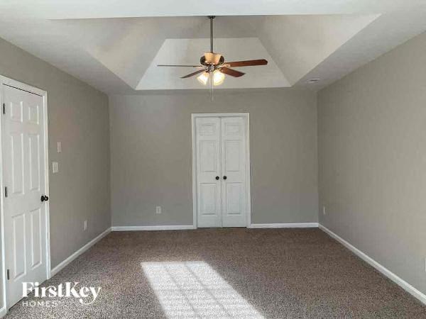 an empty bedroom with a ceiling fan and a door
