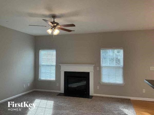 an empty living room with a ceiling fan and a fireplace