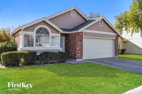 the front of a house with a driveway and lawn
