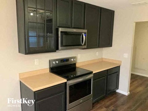 A kitchen with black cabinets and a stove top oven.
