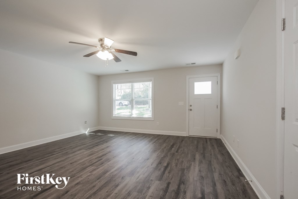 a living room with white walls and a ceiling fan